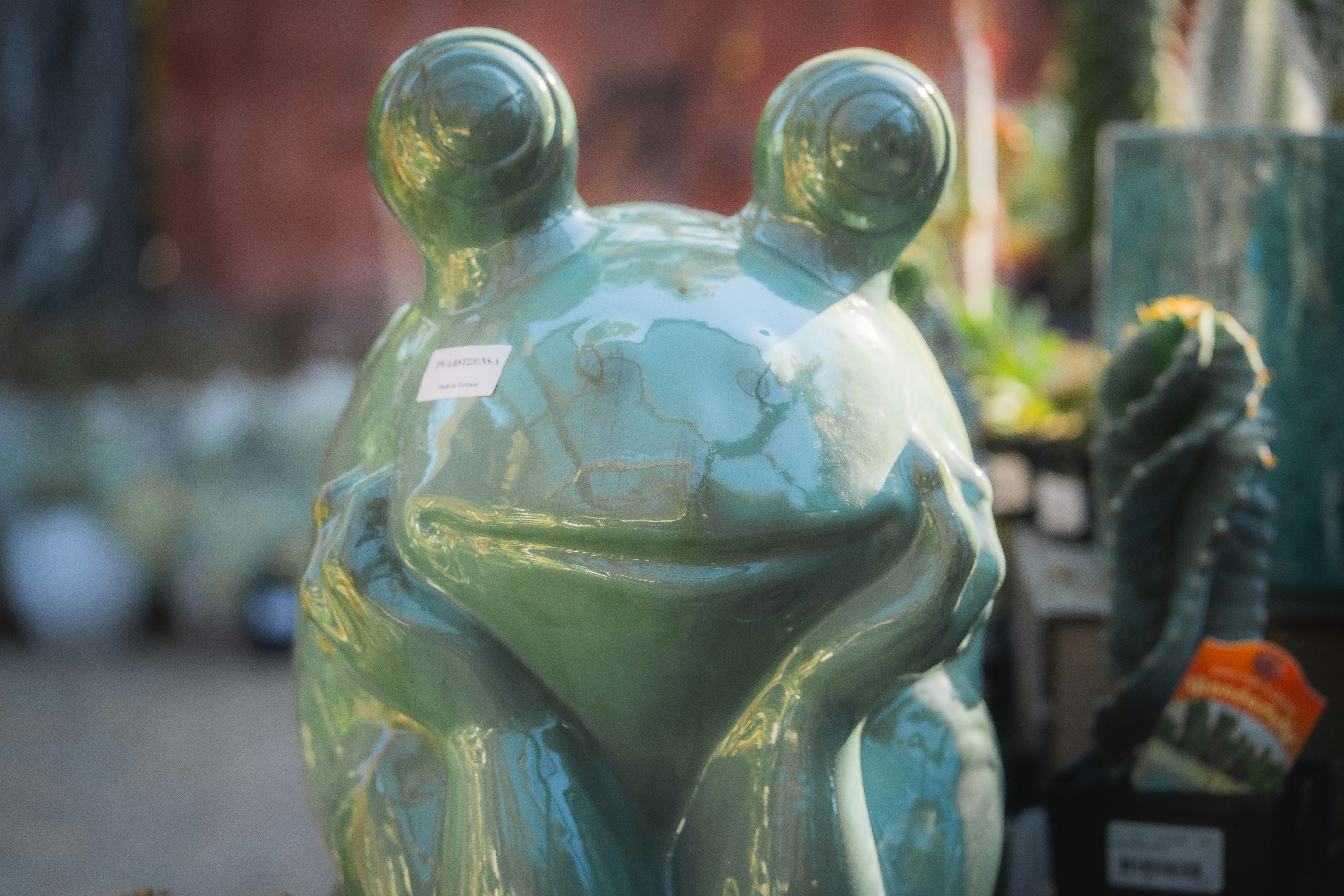 An extreme close up of a ceramic frog placed in a garden.