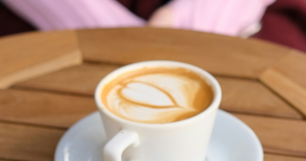 A woman sitting at a table with a latte
