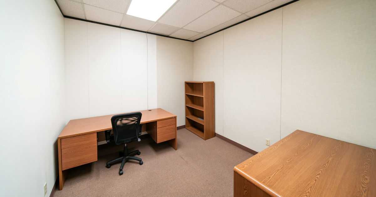 An empty office space with desk, chair, and bookcase