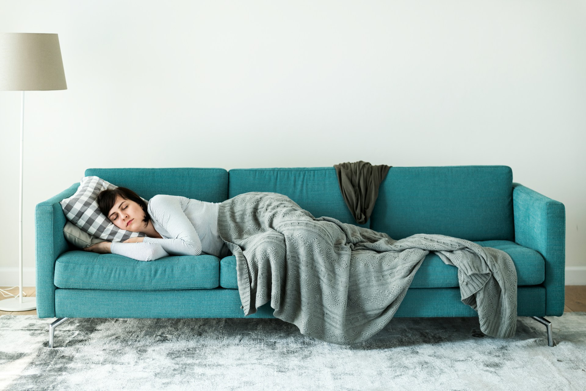 A woman sleeps on a couch in a shared living room