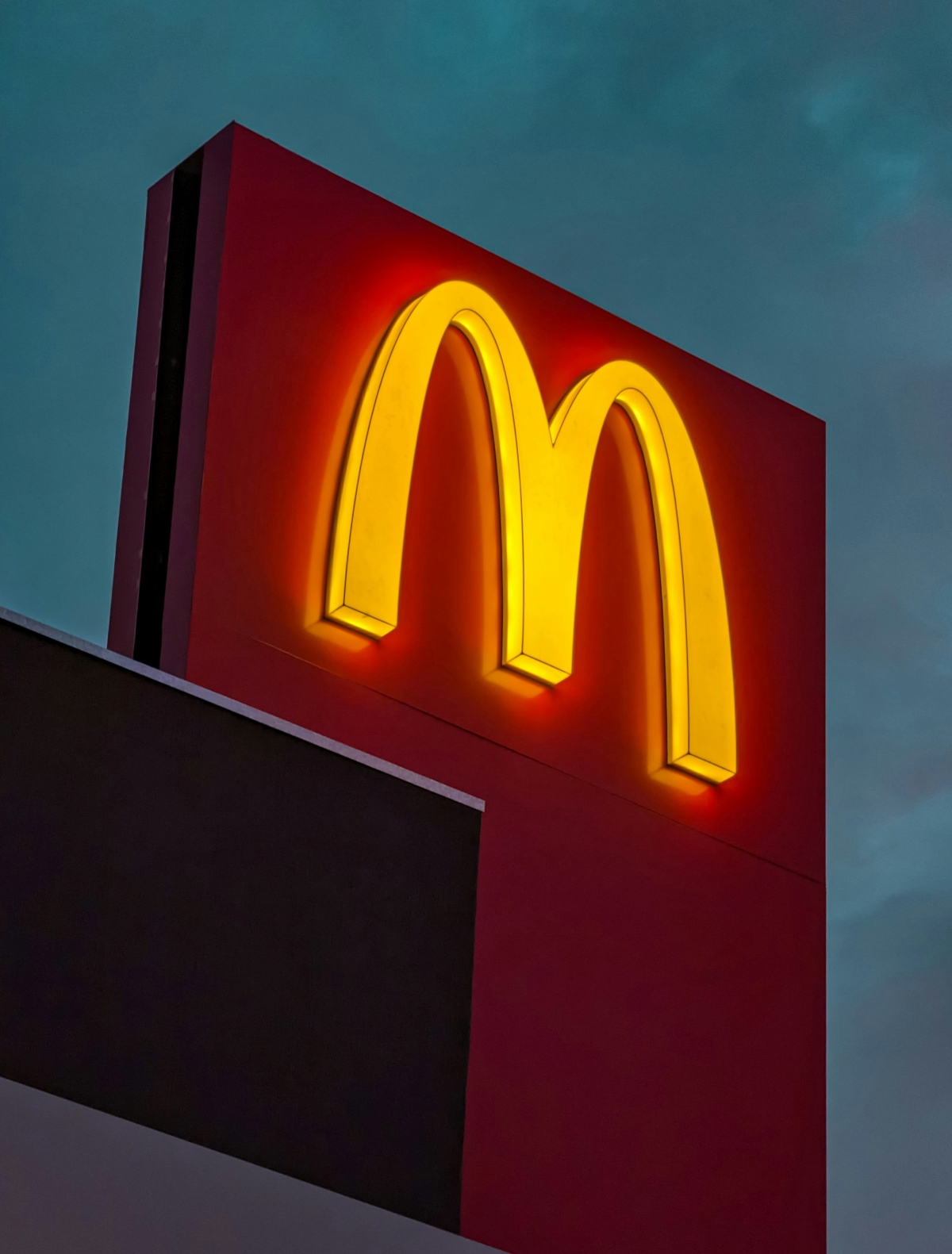 A representation of a McDonald's logo on the corner of a building lit up at night