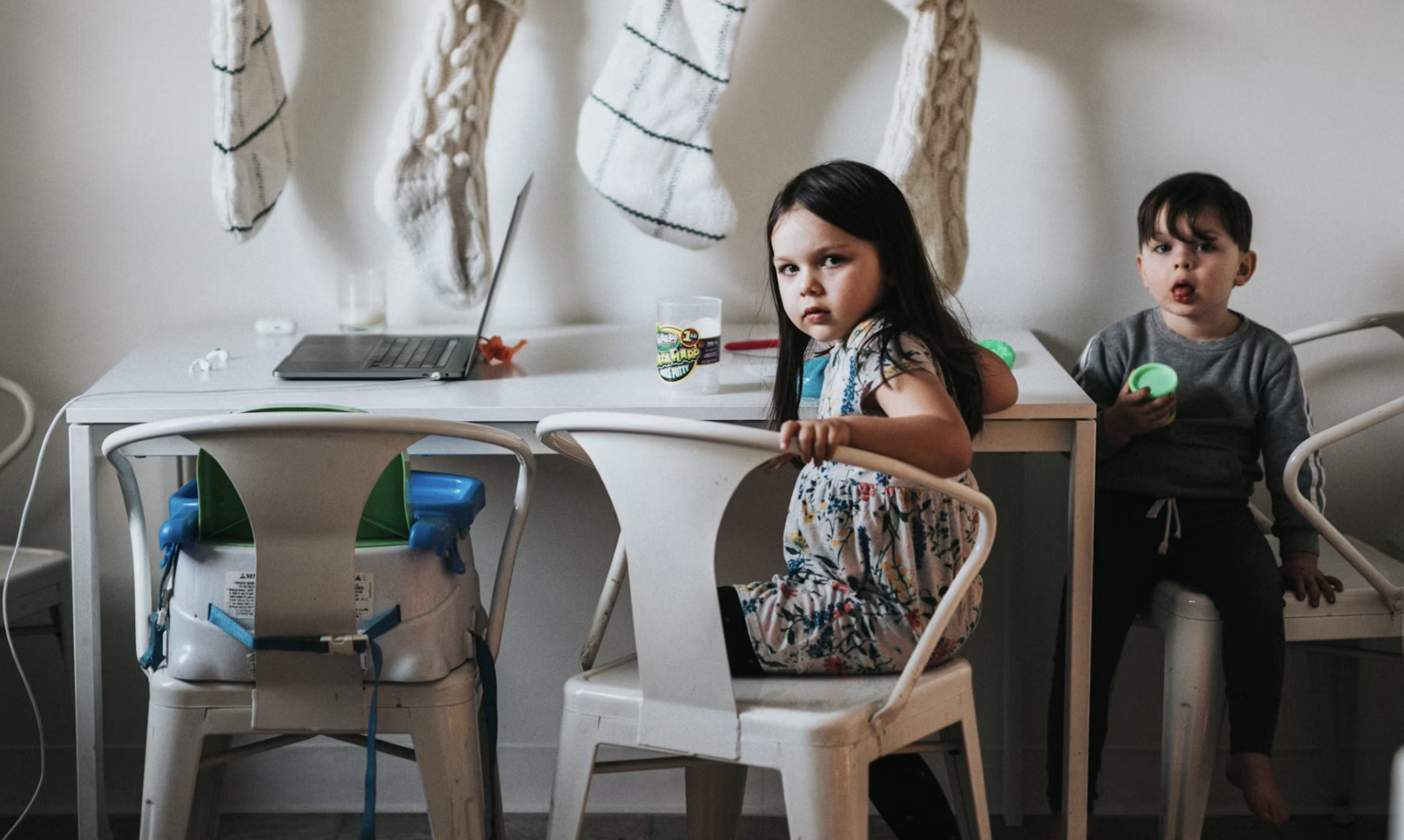 Two kids look at their mother who is working from home