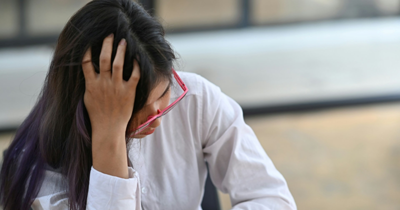 A young female employee wearing glasses runs her fingers through her hair