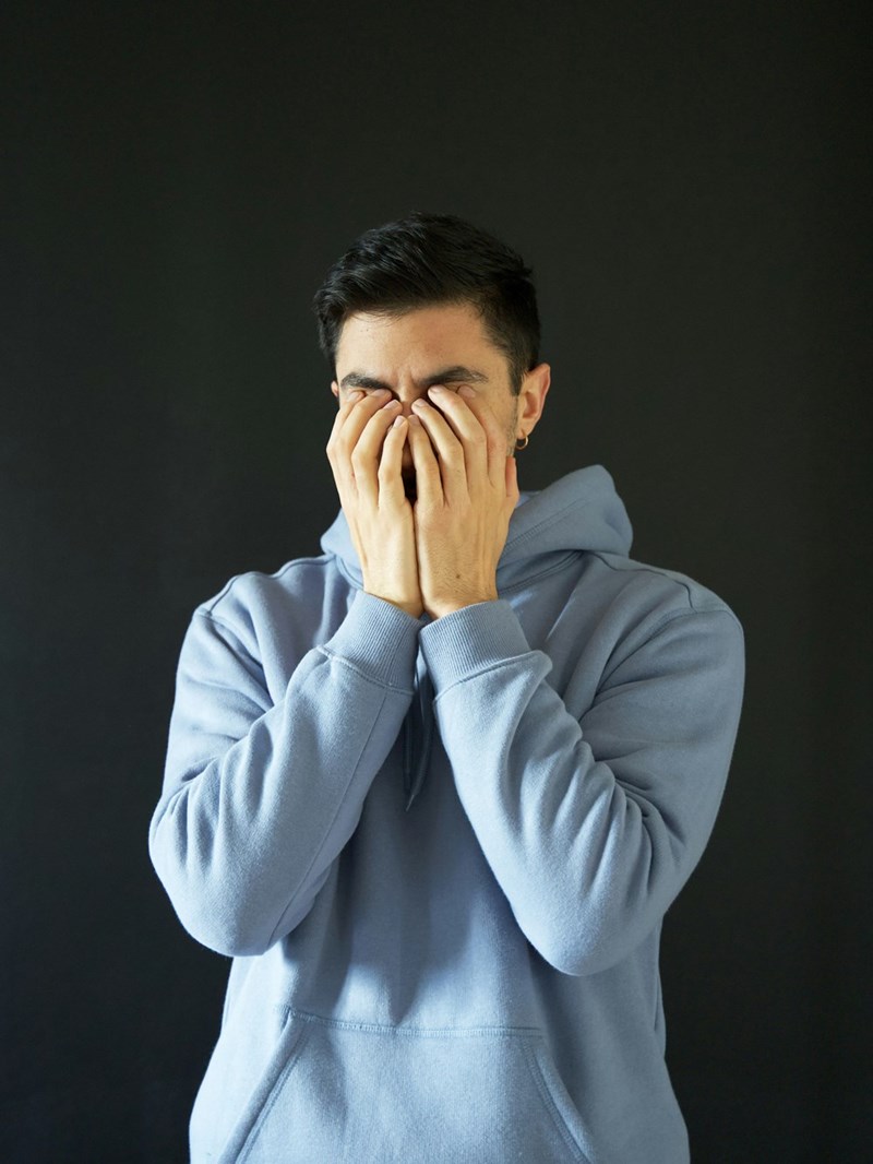 A man covers his face in frustration.