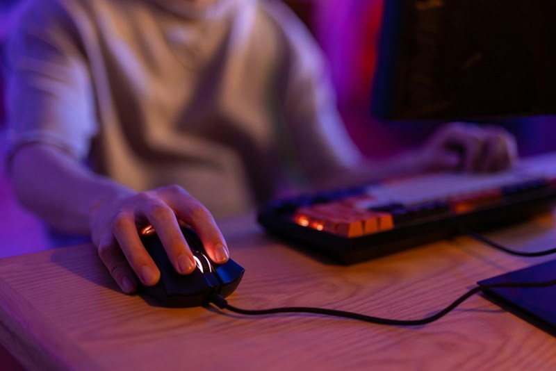 A gamer clicks using his mouse while gaming in front of his computer.