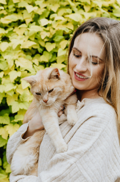 Woman hugging her cat outside, smiling.