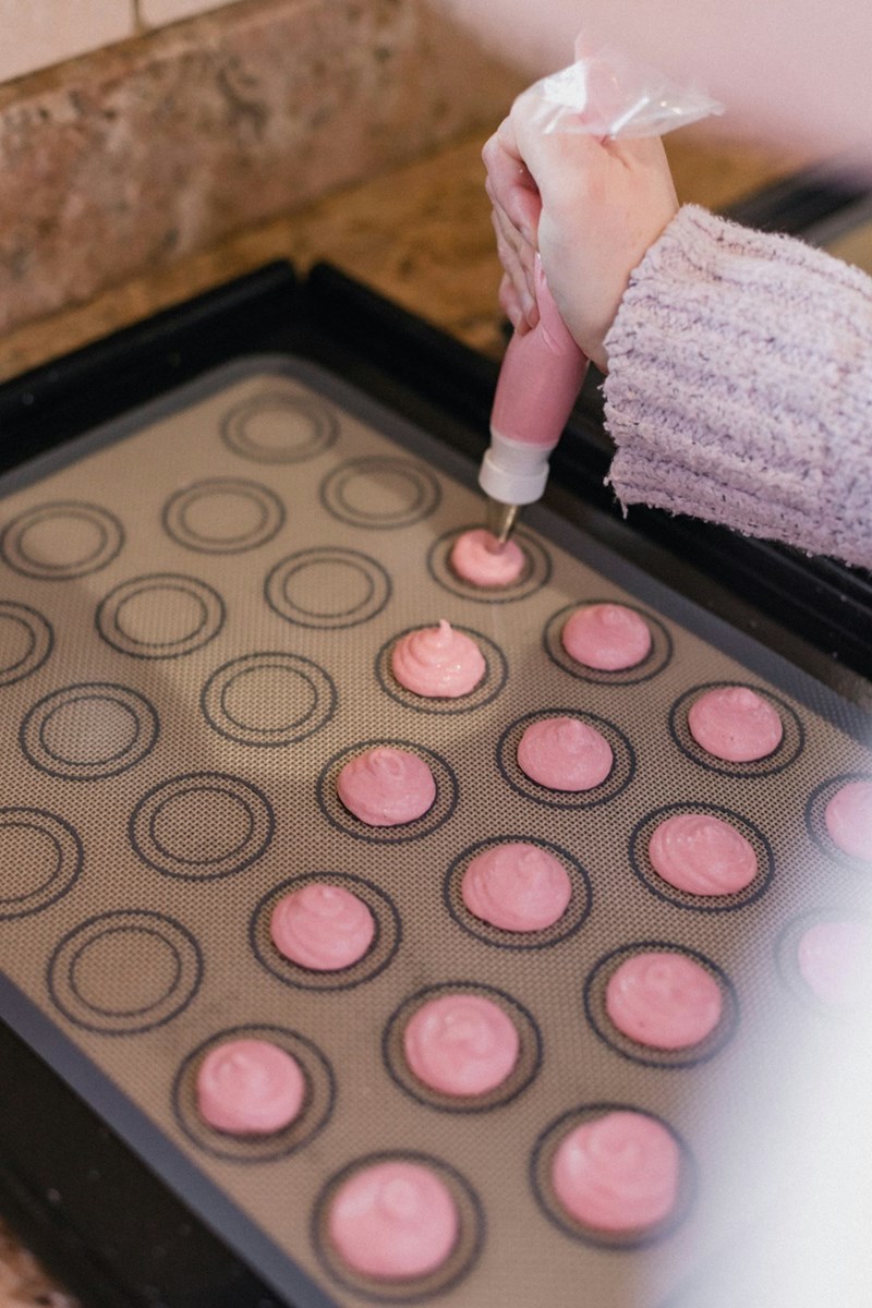 Baker piping icing and batter into a muffin tin, cafe employee