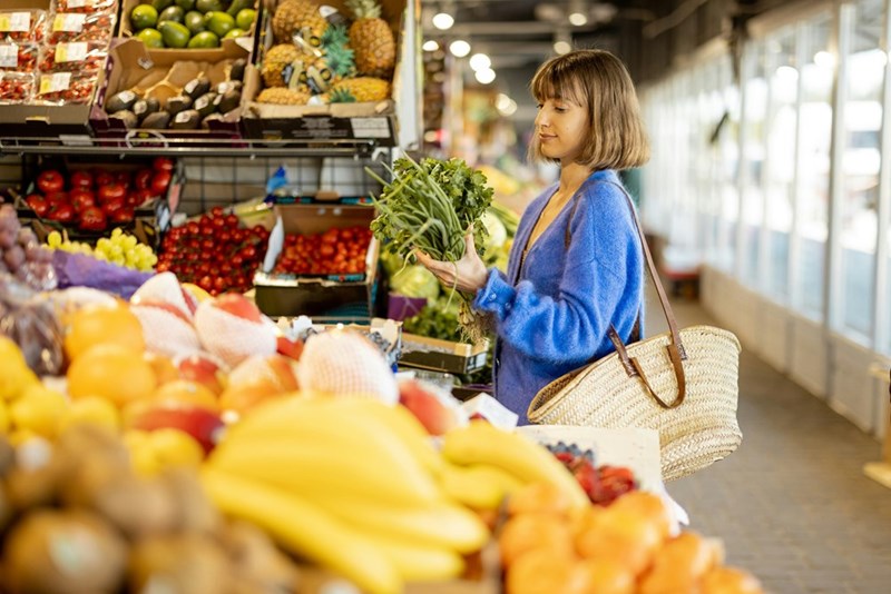 Young woman buying greens at local market