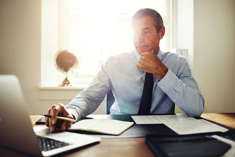The CEO of a startup company smiles, self-satisfied, as he types an online review of his own company in his private office.