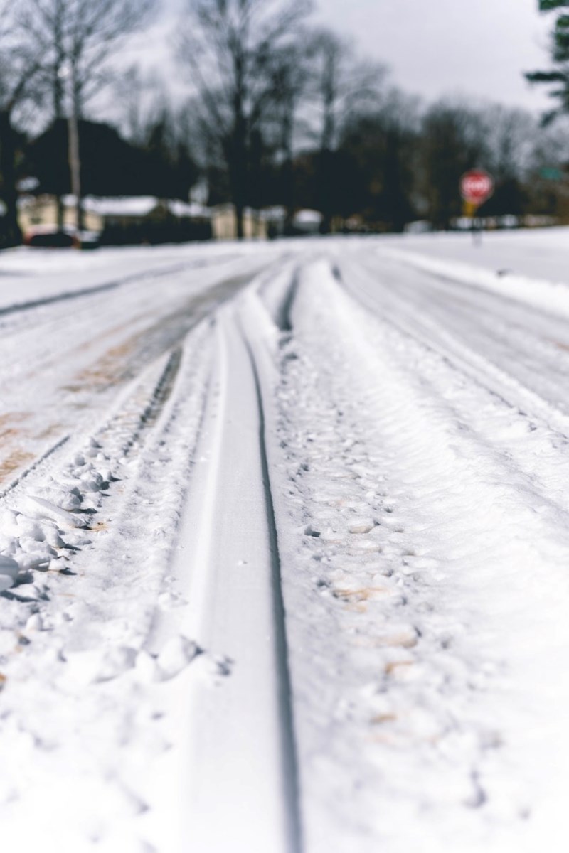 Snow-covered road with tire tracks showing hazardous commute for an employee.
