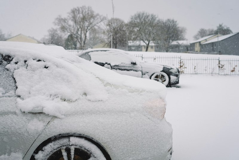 A car covered in snow is parked in a driveway