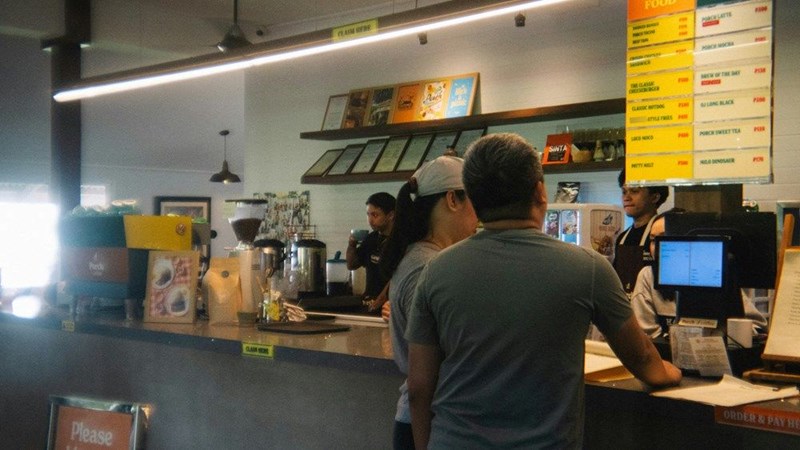 people order at a cafe counter with a menu board