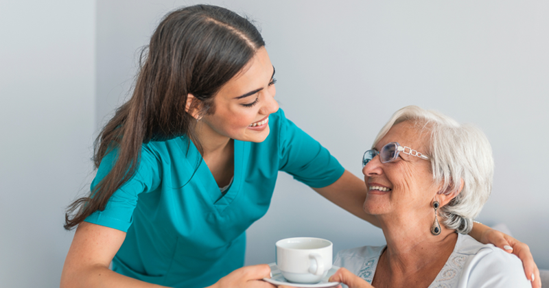 Nurse bringing tea to an elderly patient.