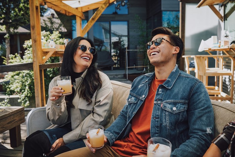 A man and a woman sitting on a couch drinking beer