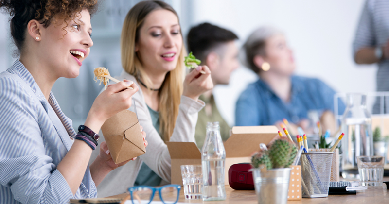 Happy coworkers eating lunch together in the break room. 