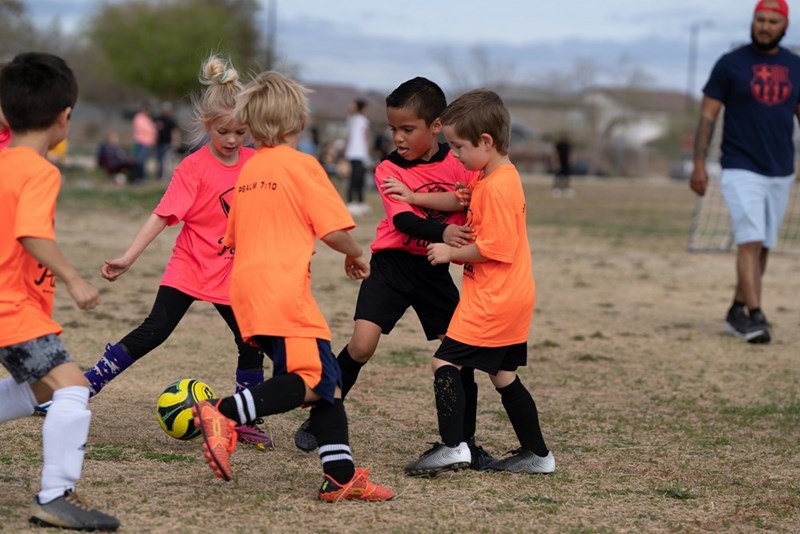 A group of young children playing a game of soccer