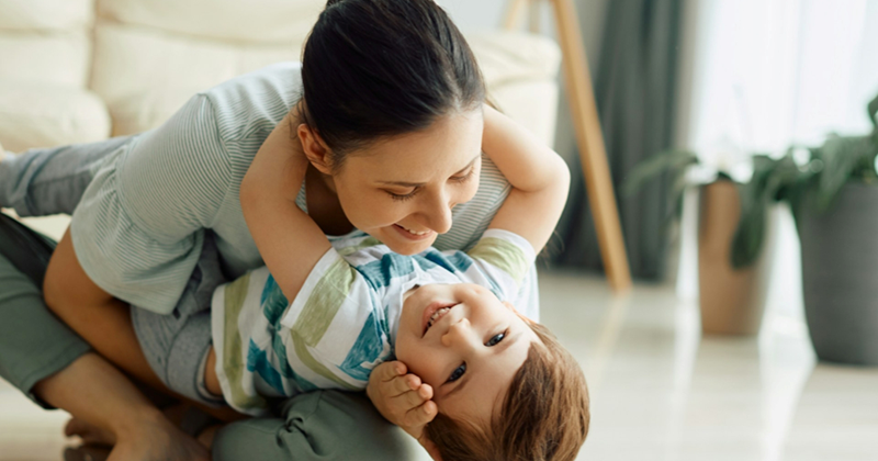 A mom holds her young son while sitting on the floor