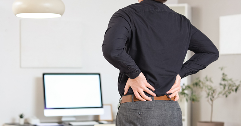 Back View of a Young Businessman Suffering from Back Pain in Office