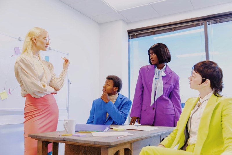 A group of agency employees wearing colorful outfits sit at a table at a meeting