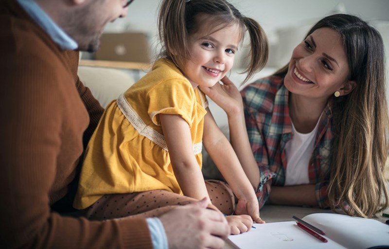 Little girl in yellow dress smiles while playing with her aunt.