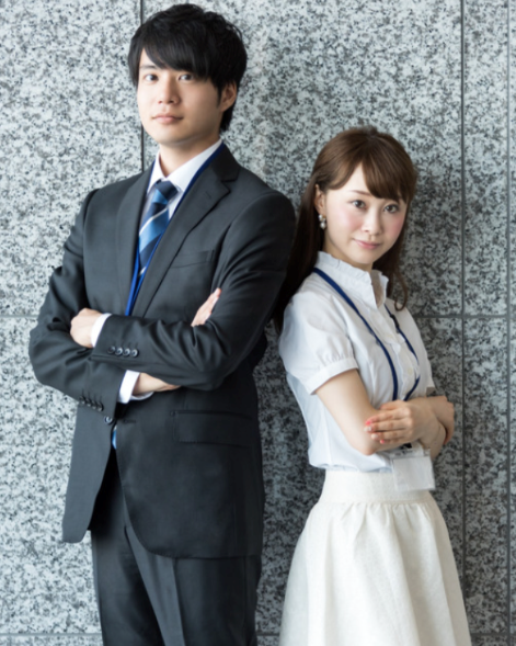 Couple standing back-to-back in the office.