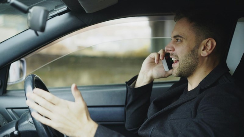 Man angrily yelling on his cellphone while driving in a car