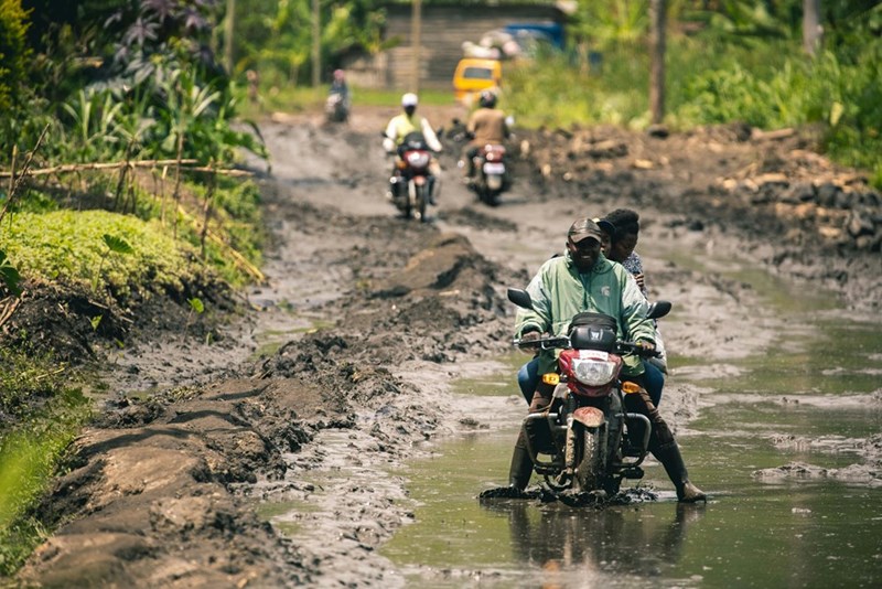 A group of people riding motorcycles down a muddy road