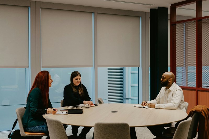 A group of people sit around a table at work