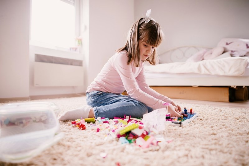 A little girl plays with blocks on the floor.