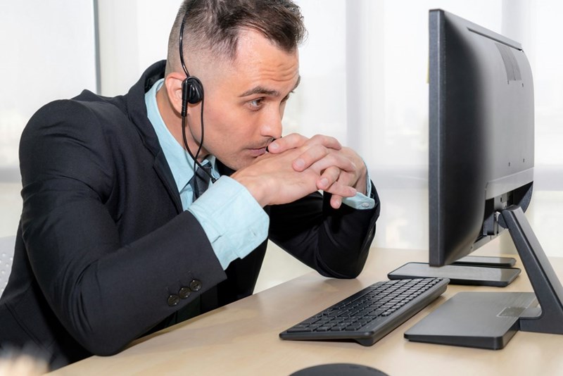 The call center manager looks suspicious as he monitors his employee's activity.