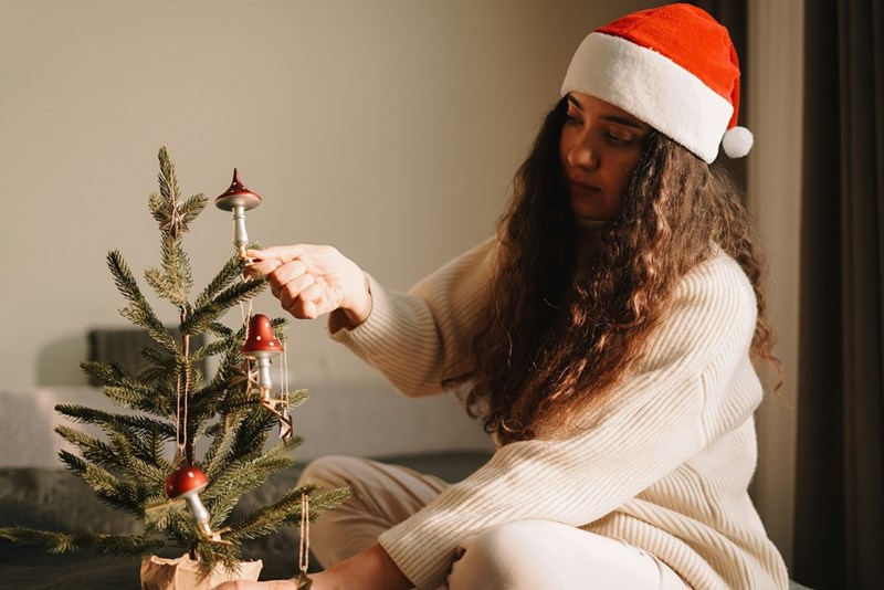 A woman in a Santa hat decorating a Christmas tree