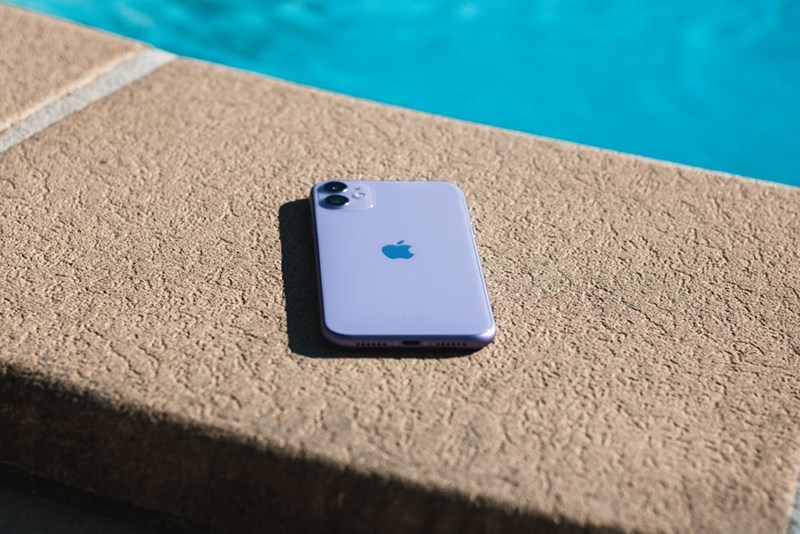 iPhone laying precariously close to water on pool edge.