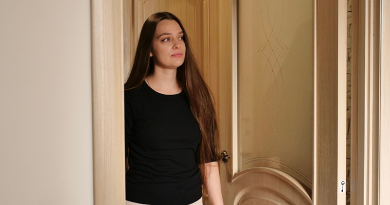 Woman looking out the front door of her apartment.