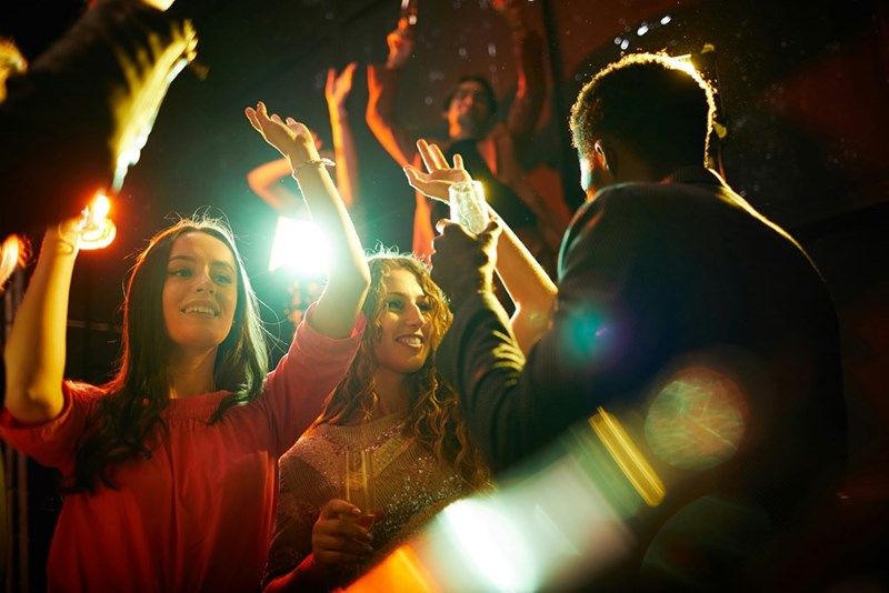 Concertgoers dance with hands in the air.