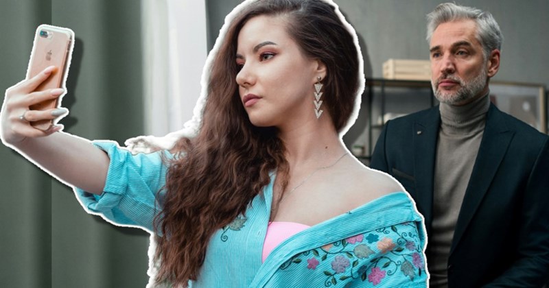 Irritated boss looks at employee who's taking a selfie at the office.