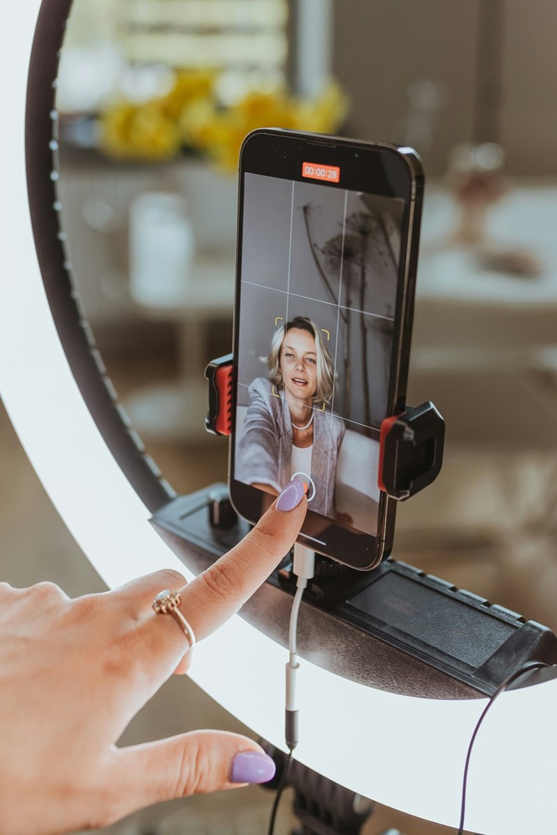 Young employee takes TikTok video with ringlight.