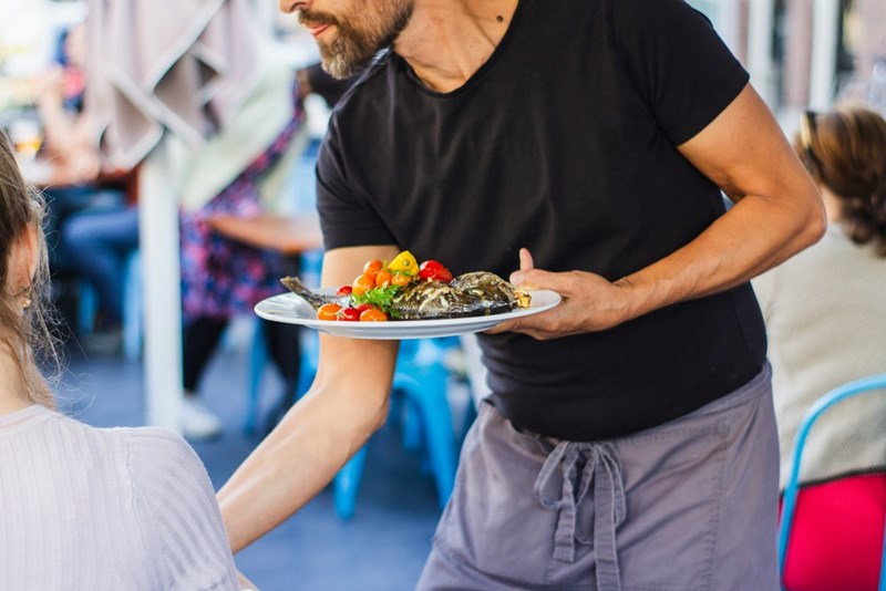 Waiter places down tray of food.