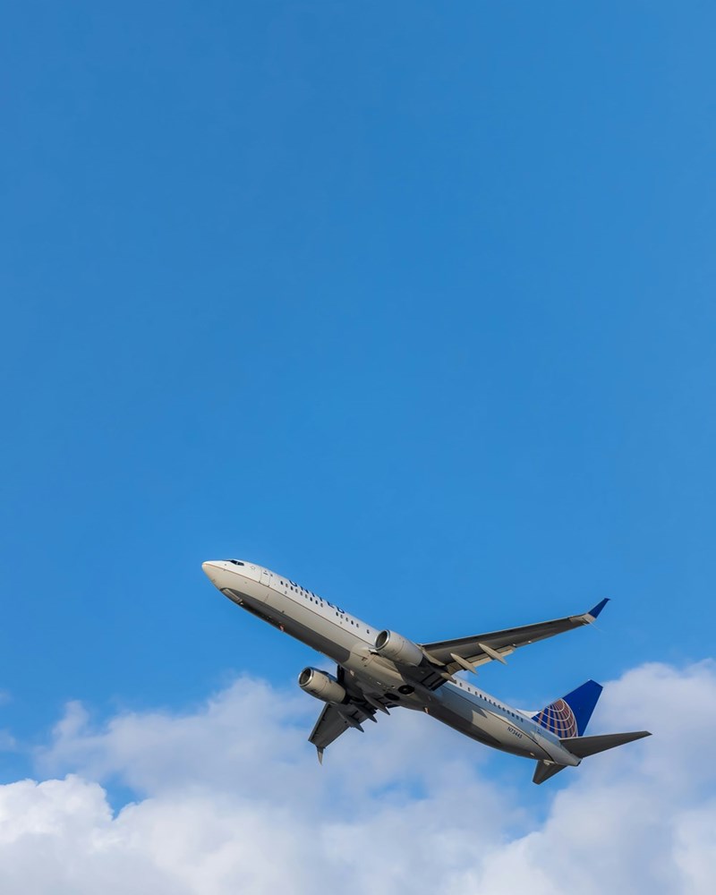 Plane flies across bright blue sky.