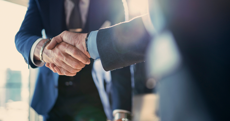 Two men in suits shaking hands.