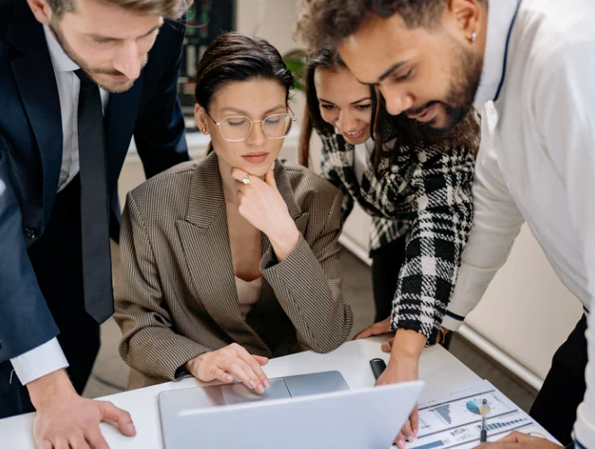 Marketing team gathered around a work presentation before showing their boss.
