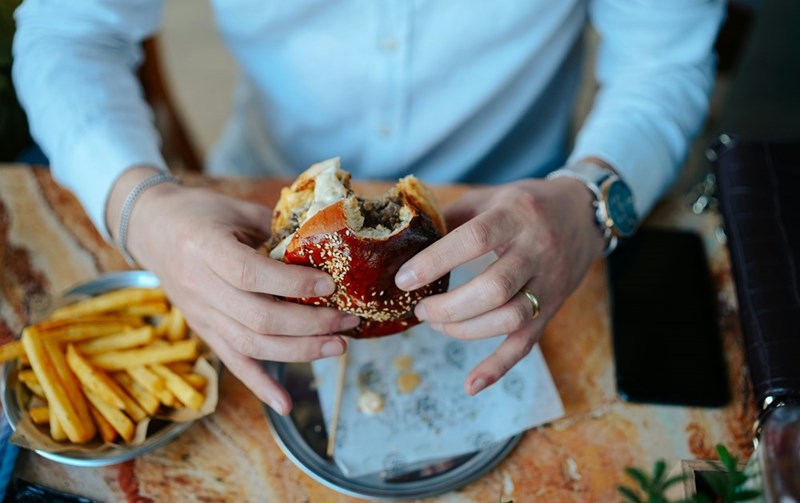 A businessman eating a burger, much to the disgust of his vegetarian client