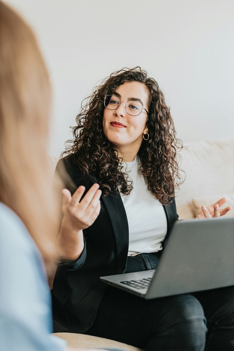 Worker looks exasperated at coworker sitting across from her as they work on laptops.