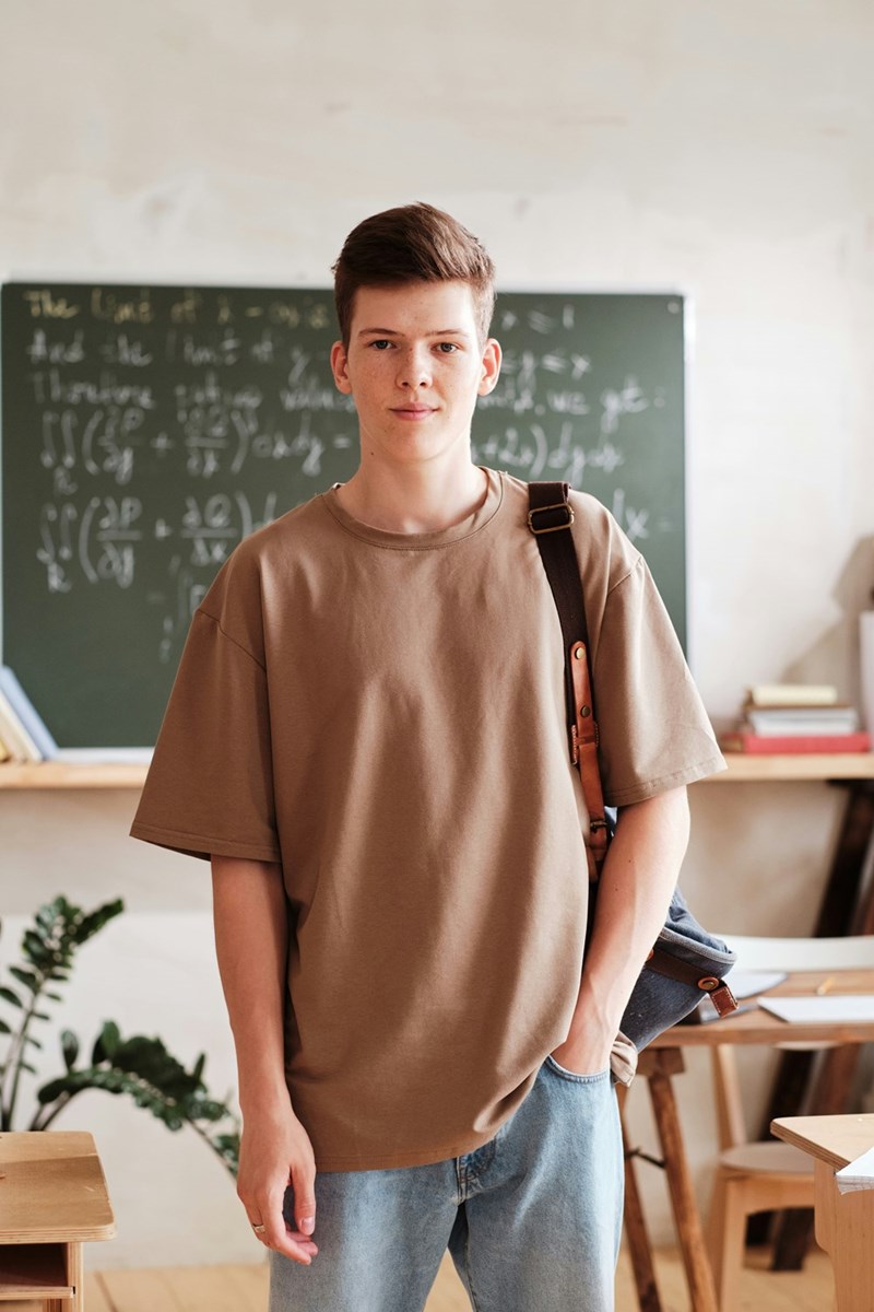 Portrait of a schoolboy with backpack looking at the camera while standing in the classroom