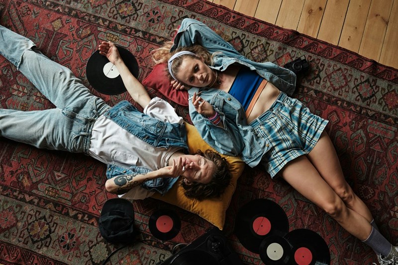 Young couple lying on rug with vinyl records,