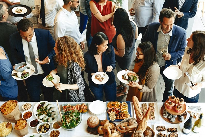 A large group of people standing around a catered buffet