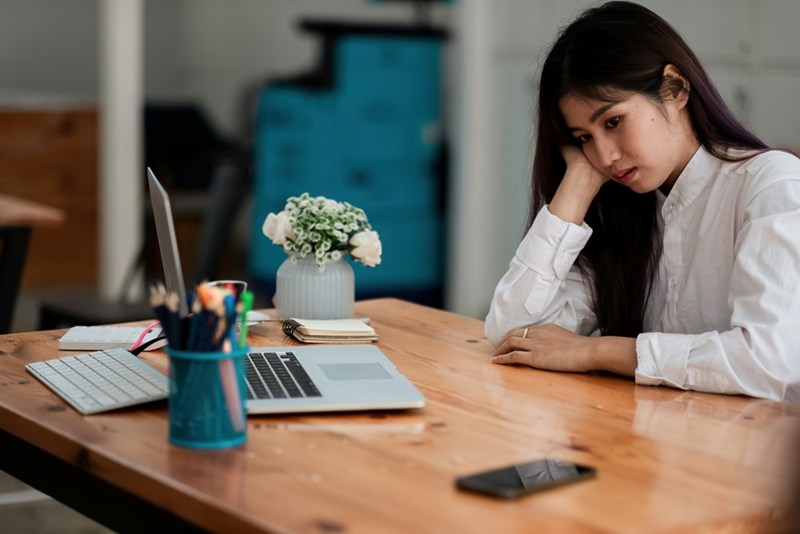 A female worker sits an a desk looking despondent