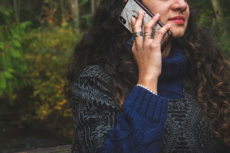 A woman in a blue sweater holds a phone to her ear