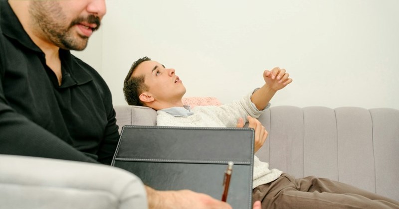 The employee lies on the couch as he speaks to the mental coach his manager set him up with at work.