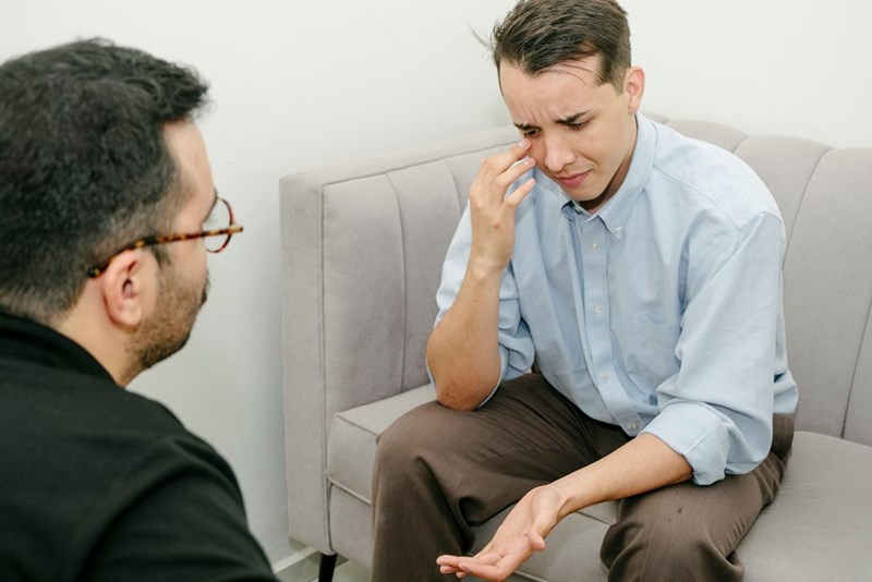 The employee sits up and wipes away tears as he opens up to the coach.