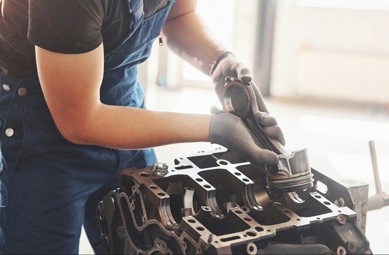 Employee working on client engine parts in a manufacturing workshop.